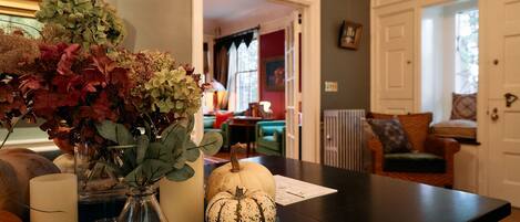 A dining table with a vase of flowers, a pumpkin, and books.