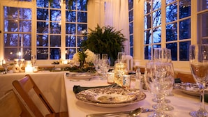 Une table dressée pour un dîner formel, avec des bougies, de la verrerie et un centre de table composé de fleurs.