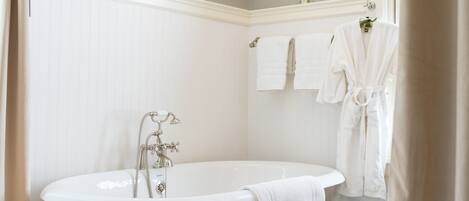 A bathroom with a freestanding bathtub, white towels, and a chandelier.