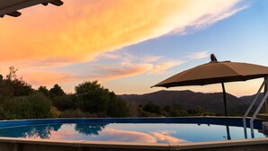 Une piscine avec vue sur les montagnes et sur le coucher de soleil.