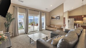 Un salon spacieux avec un grand canapé en cuir, une table basse et une vue sur un balcon.