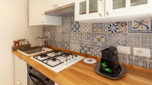 Een keuken met witte kastjes, een gasfornuis en een koffiezetapparaat op het aanrecht.