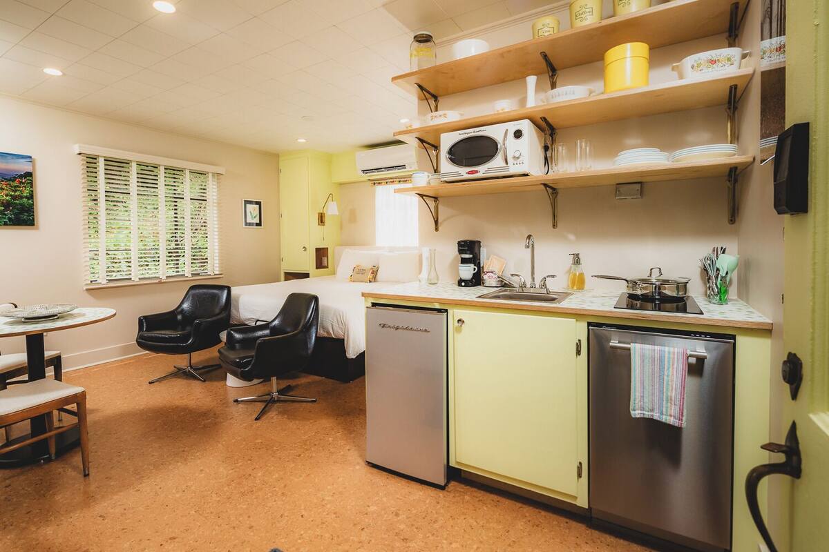 A compact kitchen with a refrigerator, microwave, and sink. There is a dining area with a table and chairs.