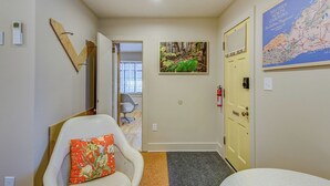 A hallway with a white chair, a map on the wall, and a door. - Blue Ridge Tourist Court (Boone)