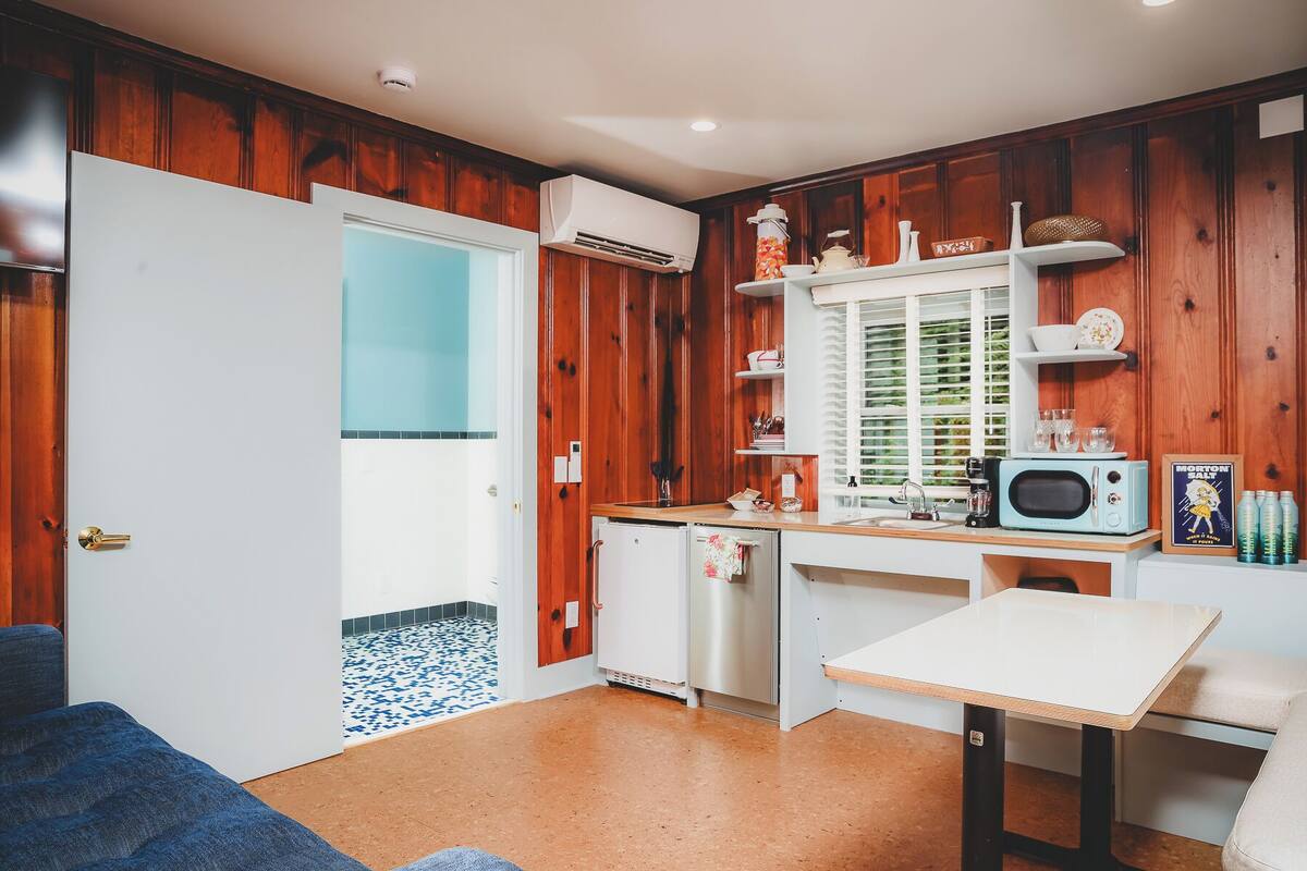 A compact kitchen with wooden paneling, a white fridge, a microwave, and a small table.
