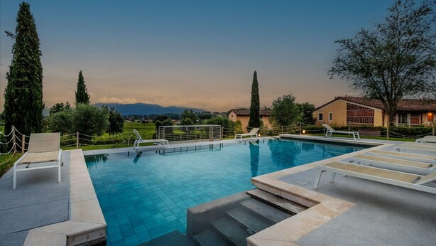 A swimming pool with steps leading into it, surrounded by lounge chairs and a view of mountains in the background. - Donato one bedroom Farmhouse Apartment with shared Pool in Fattoria Sardi Wine Resort in Lucca (Monte San quirico)