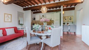 A dining area with a wooden ceiling, a round table with chairs, and a vase with flowers. - Donato one bedroom Farmhouse Apartment with shared Pool in Fattoria Sardi Wine Resort in Lucca (Monte San quirico)