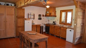 Una cocina rústica con armarios de madera, salpicadero de azulejos y una mesa de comedor de madera.