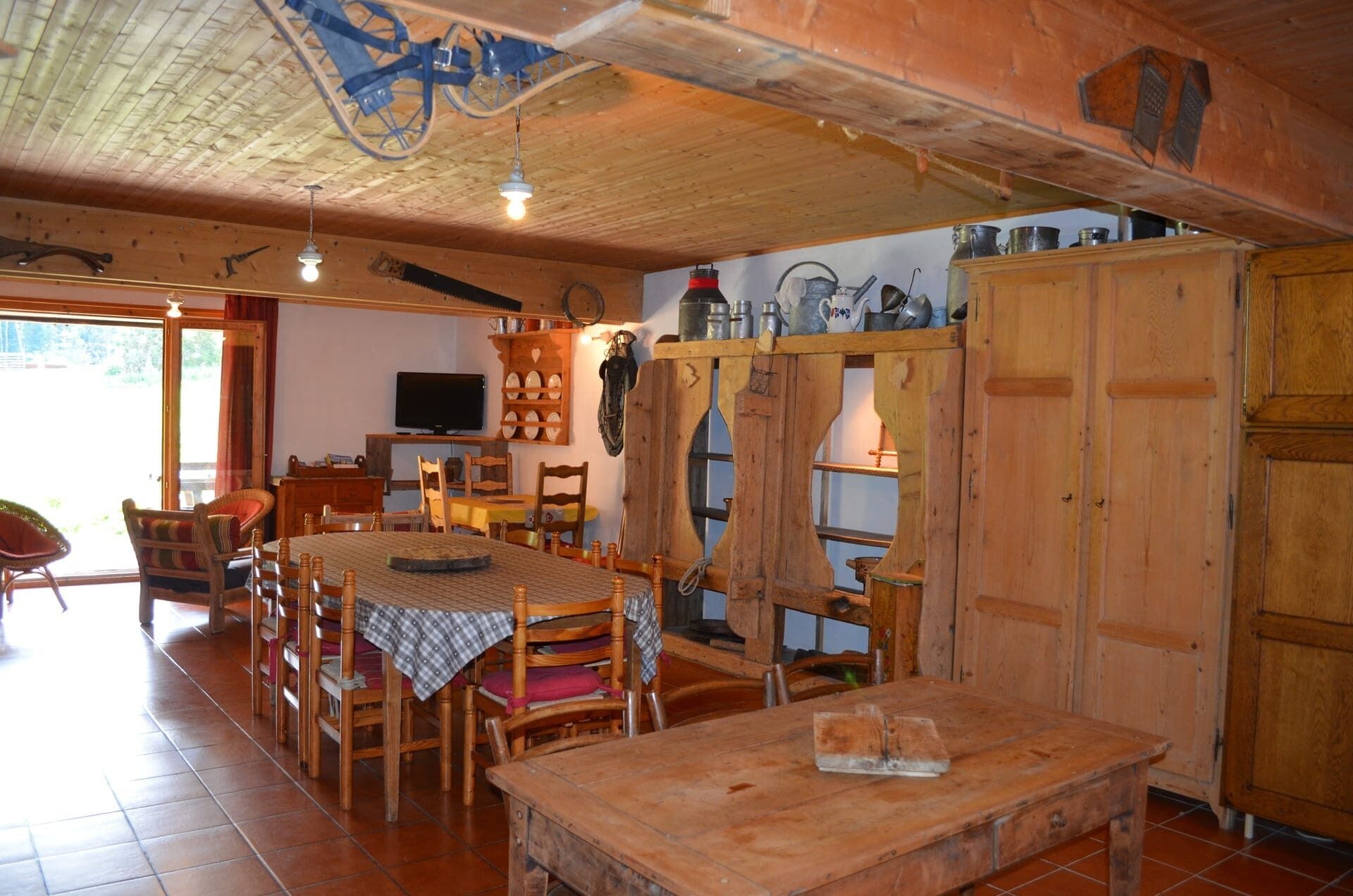Un coin repas rustique, avec des meubles en bois, un téléviseur et un espace cuisine doté de placards et d’étagères en bois.