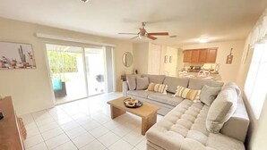 A living room with a sofa, a coffee table, and a ceiling fan. There is a sliding glass door leading to a patio. - PGA 3/2 w Backyard close to everything beach mall (West Palm Beach)