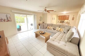 Relax in this spacious living area with a plush sectional sofa, wooden coffee table, and sliding glass door leading to an outdoor space.
