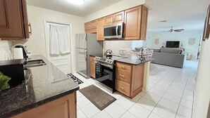 A kitchen with wooden cabinets, a microwave, a refrigerator, and a stove. - PGA 3/2 w Backyard close to everything beach mall (West Palm Beach)