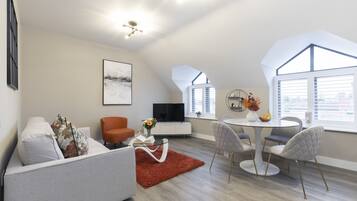 A modern living room with a sofa, a coffee table, and a dining area with chairs and a table.