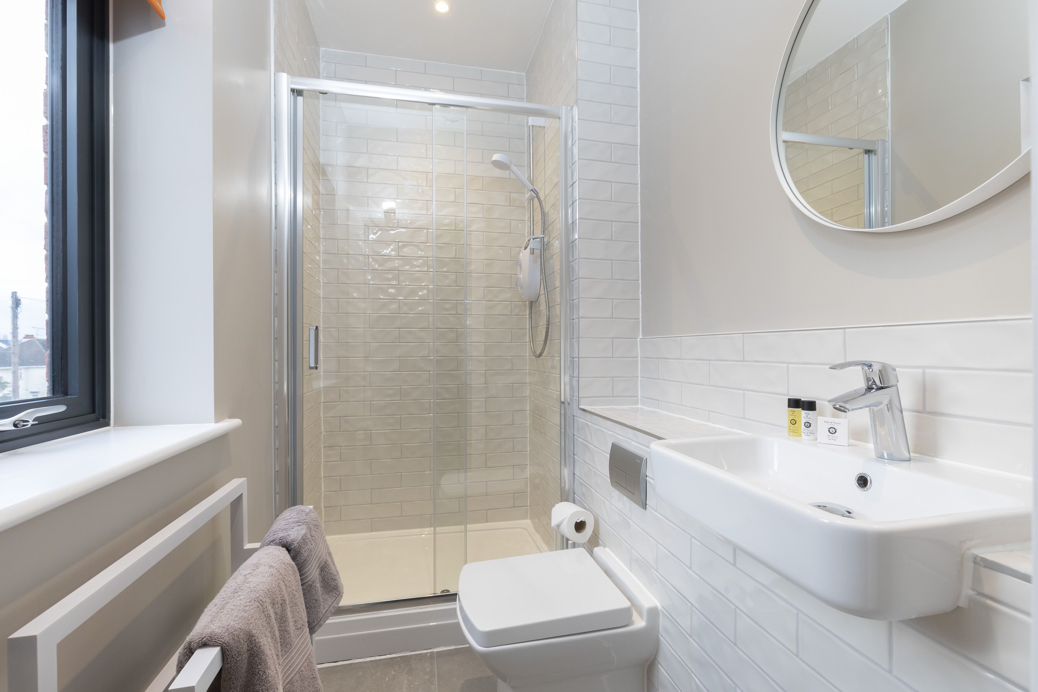 A modern bathroom with a glass-enclosed shower, a white sink, and a toilet.