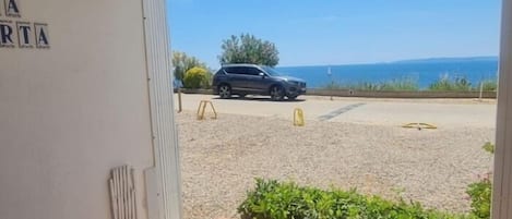 A view from a room with a window overlooking a parking area and a body of water.