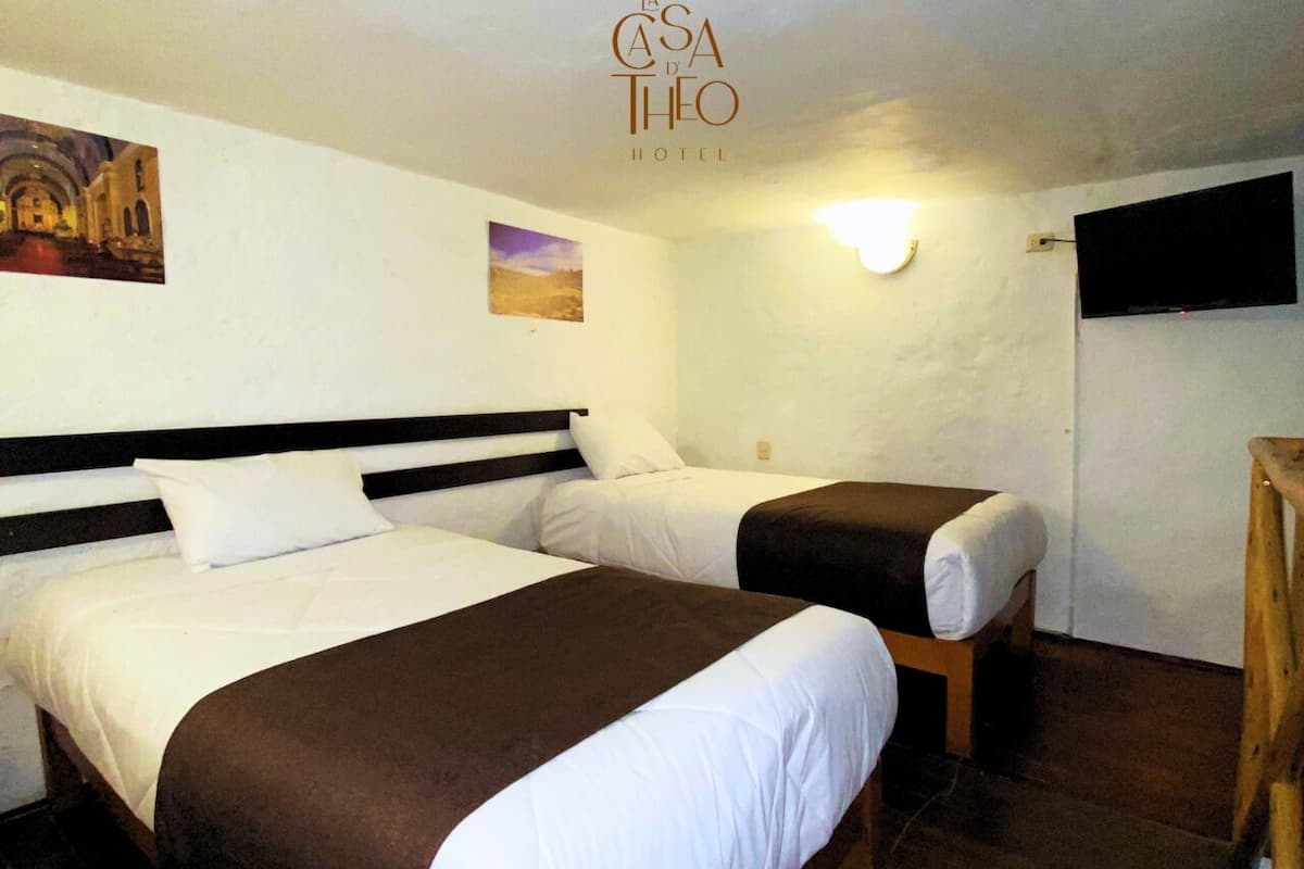 A hotel room with two beds, a flat-screen TV mounted on the wall, and a painting above the beds.