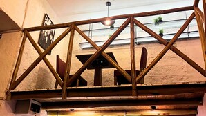 Una estructura de madera con cerchas, un ventilador de techo y un letrero que dice 'La Casa de Theo Hotel'.
