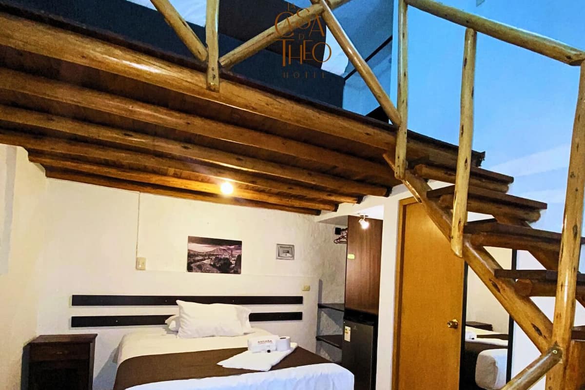 A bedroom with a wooden ceiling, a bed with white linens, a nightstand, and a door leading to another room.