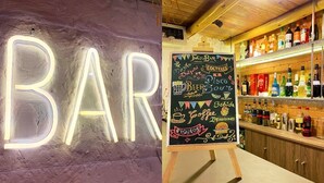 Un bar con un letrero de neón y una pizarra que anuncia bebidas y café.