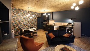 A compact living space with a dining area, a sofa, a washing machine, and a kitchenette. - Duplex spa (Bagnères-de-Bigorre)