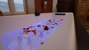 A bathtub filled with water and rose petals. - Duplex spa (Bagnères-de-Bigorre)