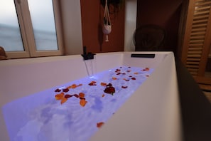 A bathtub filled with water and rose petals.