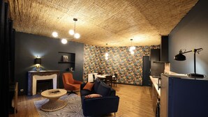 A cozy living room with a fireplace, a dining area, and a kitchen. - Duplex spa (Bagnères-de-Bigorre)