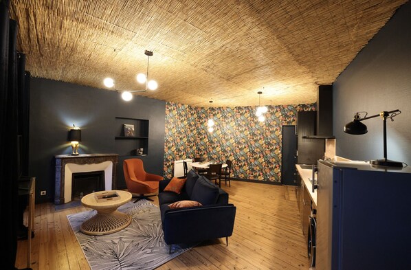 A cozy living room with a fireplace, a dining area, and a kitchen.