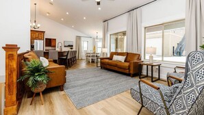 Ein geräumiges Wohnzimmer mit Sofa, Sessel und einem Essbereich im Hintergrund.