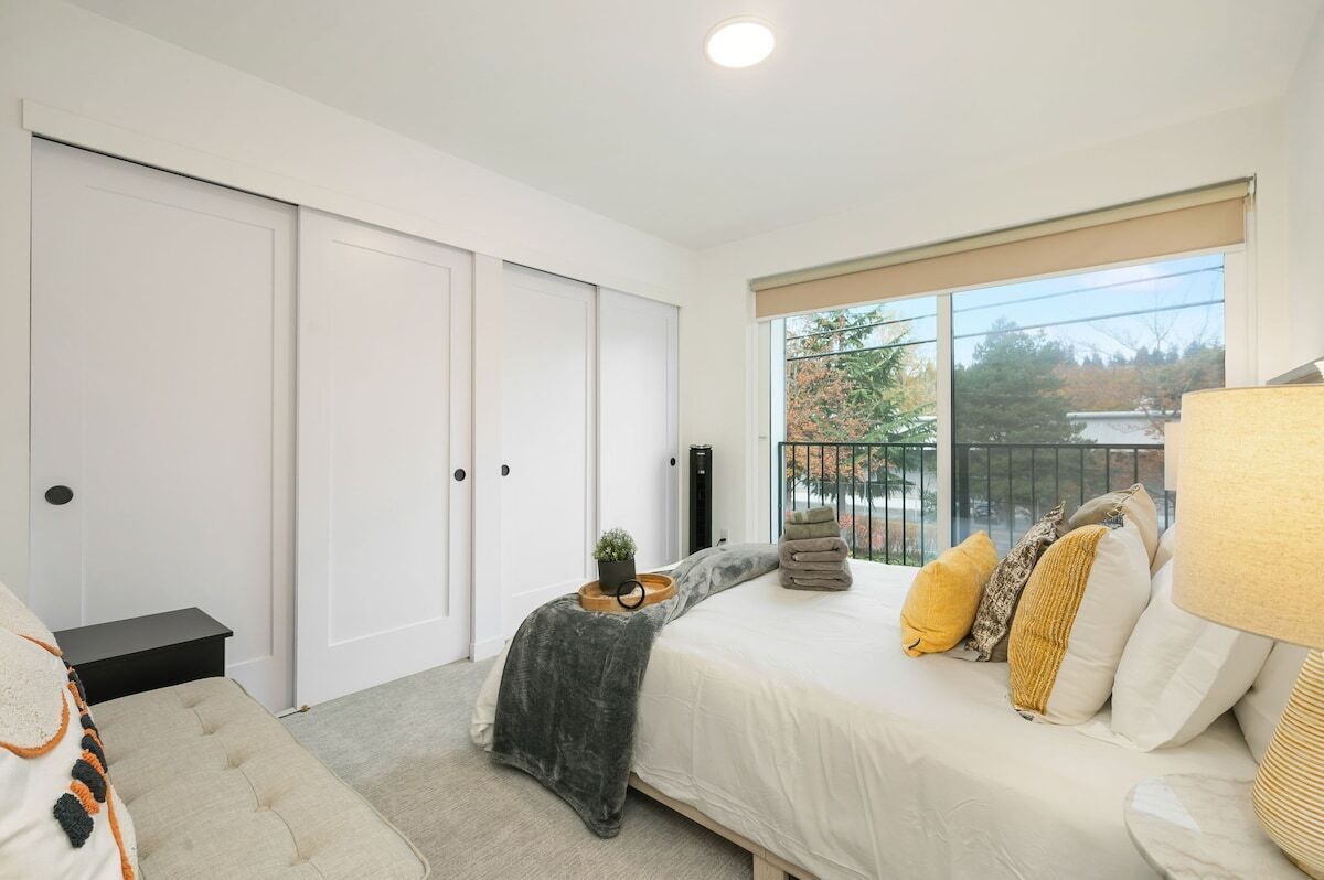 A bedroom with a bed, bedside tables, a window with a view, and a door.