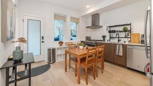 A compact kitchen with a dining area, a built-in stove, and a refrigerator. - Perch - Sand Point Haven: Spacious 3BR w Parking|UW & Children's hospital (Seattle)