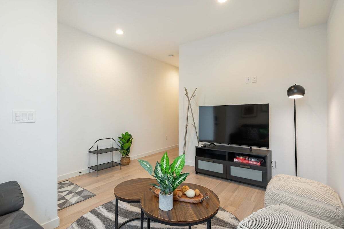 A modern living room with a sofa, a coffee table, a TV stand, and a floor lamp.