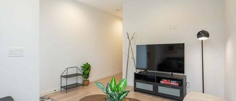 A modern living room with a sofa, a coffee table, a TV stand, and a floor lamp.