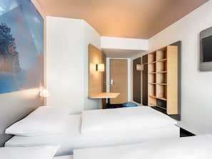 Una habitación de hotel moderna con cama, mesitas de noche, armario y televisor de pared.