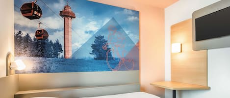 A modern hotel room with a large bed, a mounted TV, and a wall-mounted shelf.