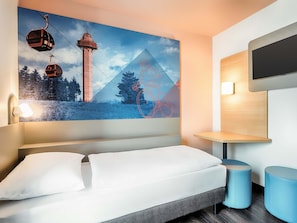 A modern hotel room with a large bed, a mounted TV, and a wall-mounted shelf. - B&B Hotel Willingen (Willingen)