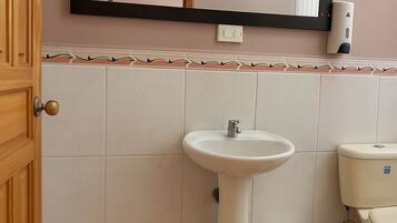 Une salle de bain avec un lavabo blanc, un miroir et des toilettes.