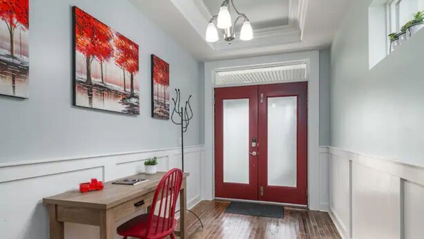 A hallway with a wooden desk, red chair, and artwork on the wall. - Chestnut Street Charmer-Walk to Louisville! (Jeffersonville)