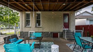 An outdoor patio with a wooden ceiling, a table with chairs, a swing set, and a patterned rug. - Chestnut Street Charmer-Walk to Louisville! (Jeffersonville)