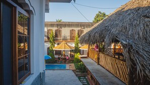 A courtyard with a pool, wooden deck, thatched-roof structures, and a stone wall. - Hotel y Restaurante Las Adas y Estrellas (Melchor de Mencos)