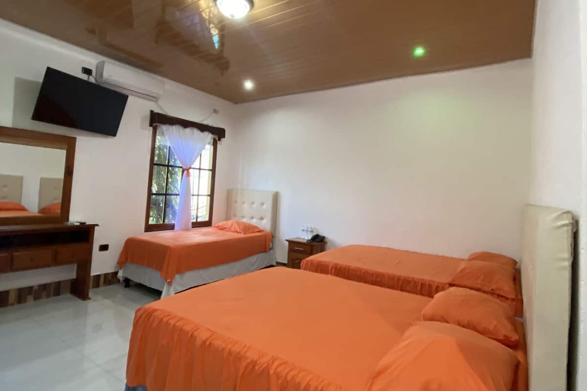 Ein Hotelzimmer mit zwei Betten, einem Fernseher und einem Deckenventilator.