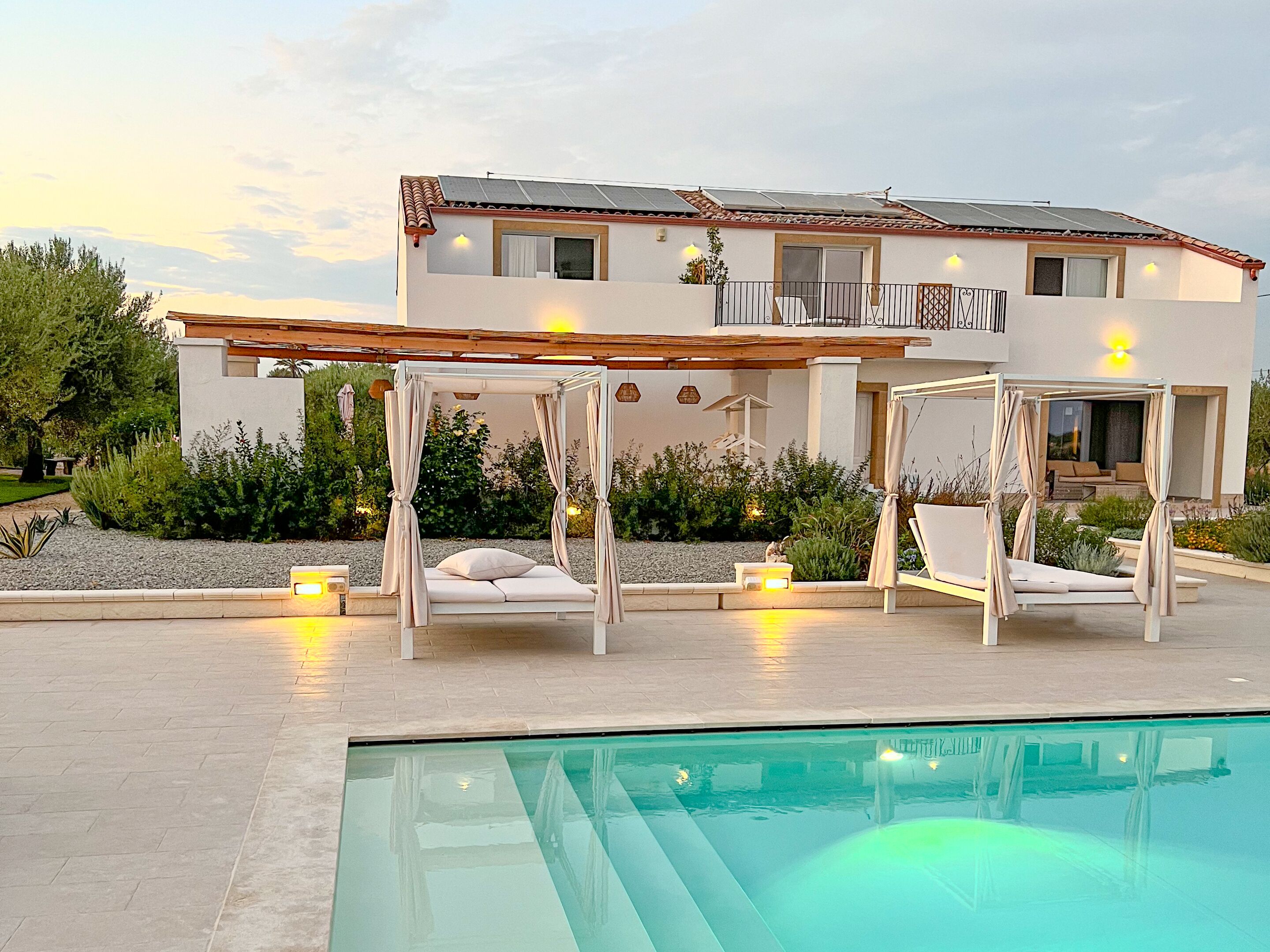 A modern villa with a pool, outdoor seating, and a well-maintained garden.