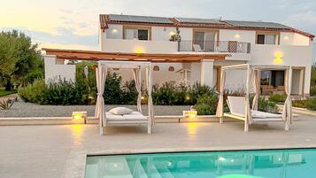 A modern villa with a pool, outdoor seating, and a well-maintained garden.