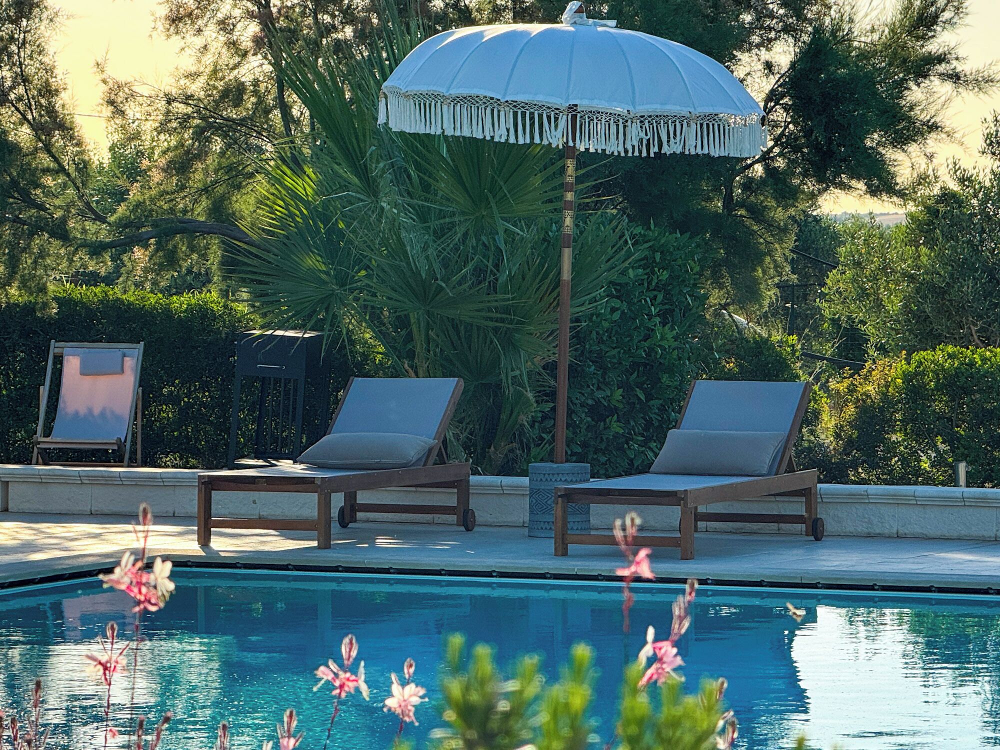 A poolside area with two lounge chairs and a large umbrella.