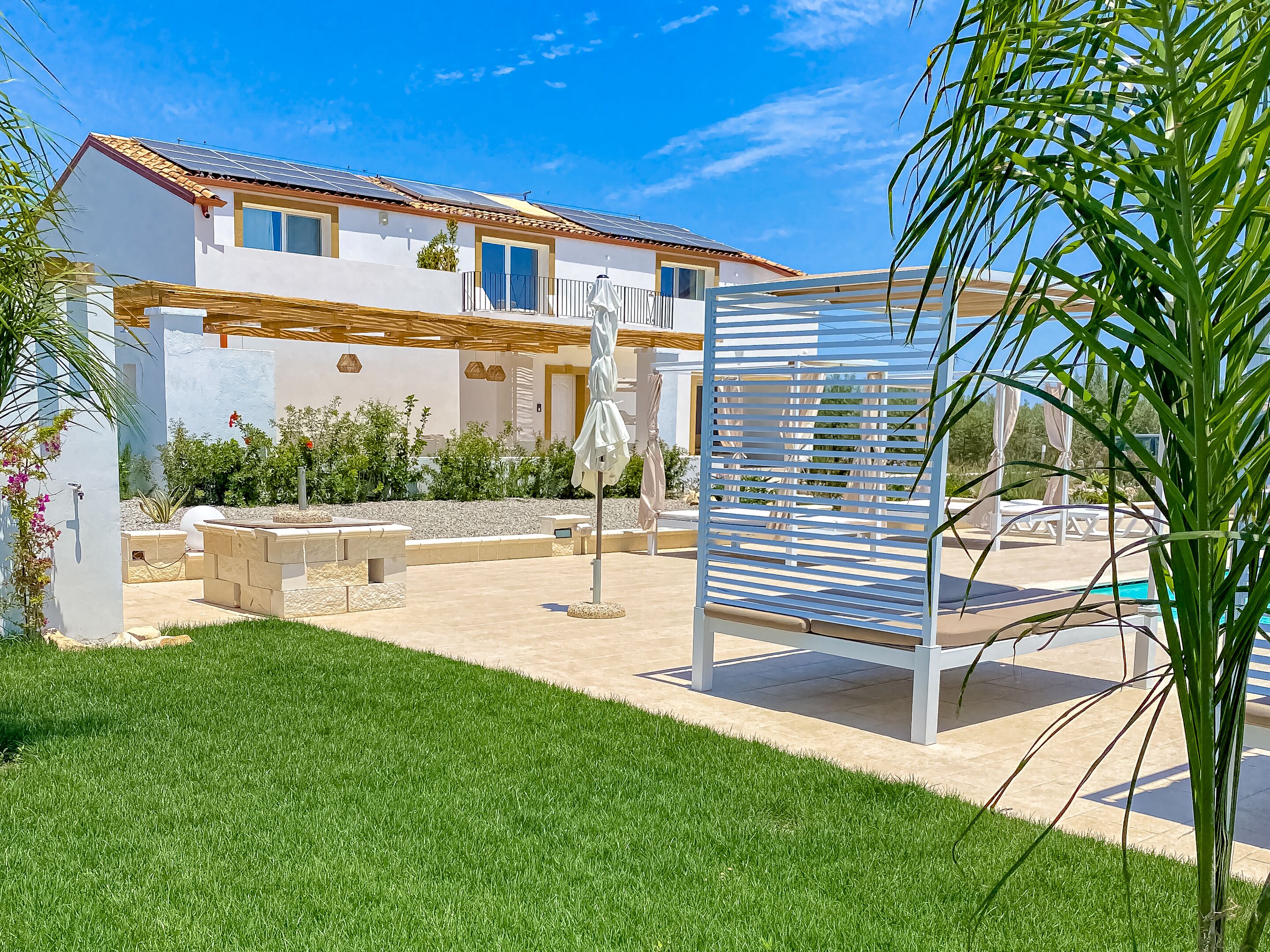 A modern house with a patio, outdoor seating, and a pool.