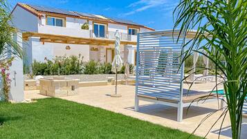 A modern house with a patio, outdoor seating, and a pool.