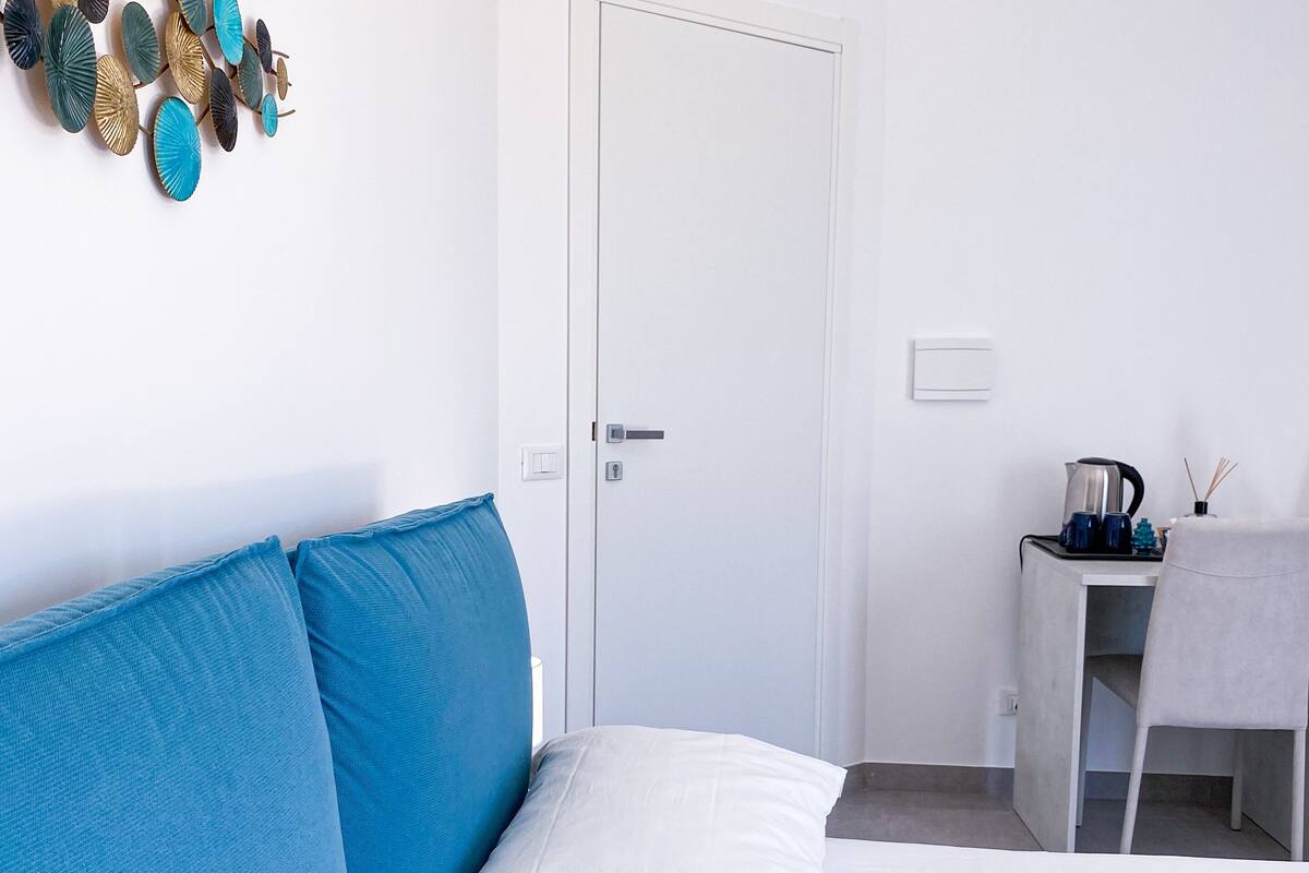 A bedroom with a bed, a desk, and a white door.