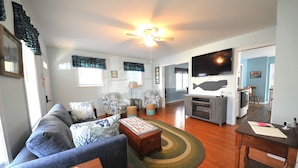A living room with a sofa, coffee table, and a television. There is a wooden cabinet and a dining table with chairs. - Walking distance to shopping, restaurants, entertainment, and the Chesapeake Bay (Rock Hall)