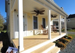 A house with a porch, two rocking chairs, and a ceiling fan.