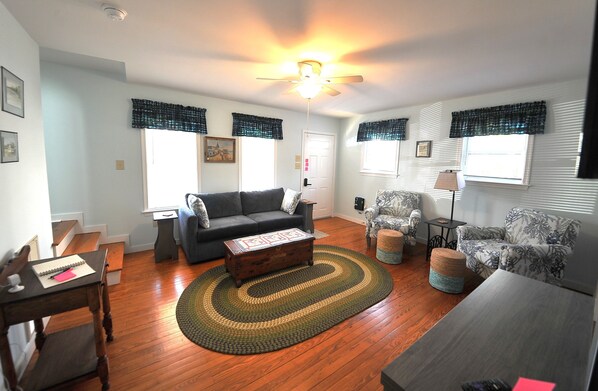 A living room with a sofa, armchairs, a coffee table, and a patterned rug.
